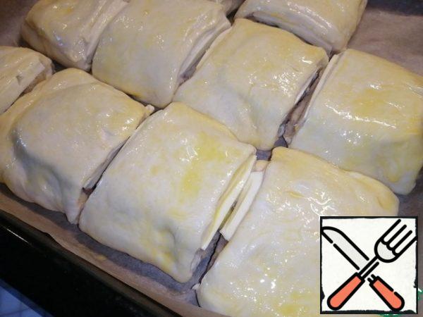 Cover the baking sheet with baking paper. To move the pieces. Grease the top with egg. Tomatoes cut into round pieces. Spread on each piece.