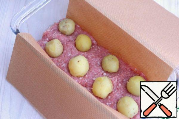 The baking dish is lined with parchment for the convenience of removing the finished mitlof.
At the bottom, put a small amount of cooked minced meat, then put the mini-potatoes, as shown in the photo. Then again a layer of minced meat and again a layer of mini-potatoes, etc.