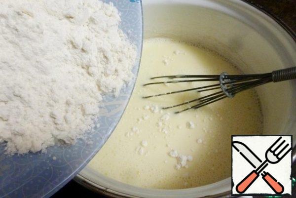 First we'll make pancakes. I have a simple classic recipe for pancakes on soda. This recipe always makes pancakes for me. The taste is neutral, soft and elastic and can be stuffed with any filling.
Whisk the eggs with the milk and water, add salt and sugar. Add flour and stir with a whisk. Let stand for 15-20 minutes.