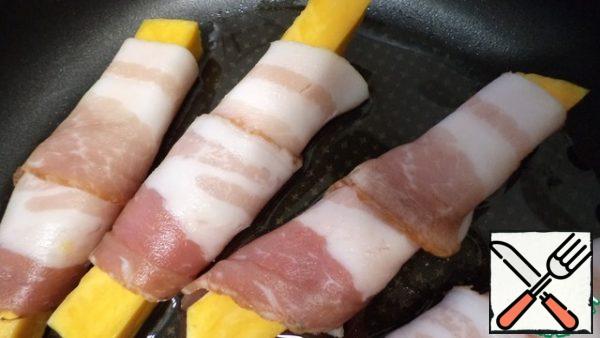 To taste, salt and pepper the pumpkin and wrap it in thin long strips of bacon.

Pour the oil into the pan and fry the pumpkin in bacon on all sides over low heat. When the pumpkin is soft, let it brown over medium heat.