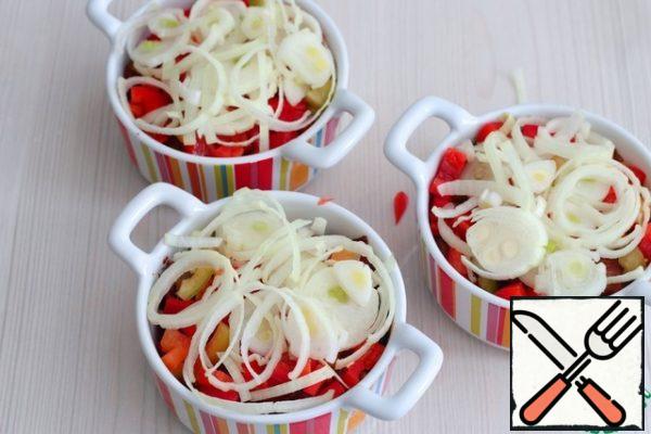 Then the shallot rings. I want to draw your attention to the fact that it is better to use shallots for this dish, because it is considered more dietary in comparison with ordinary onions, has a subtle aroma and is devoid of bitterness. Sprinkle onion rings with vegetable oil on top, add 1-2 tablespoons of broth to the molds.