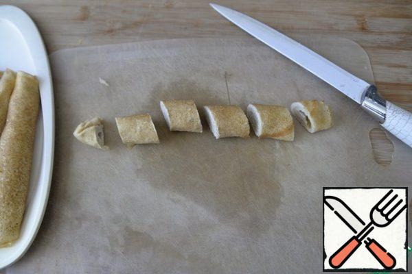 Frozen pancake rolls are taken out of the freezer, cut off the edges with a sharp knife. Cut diagonally into even 4 parts.