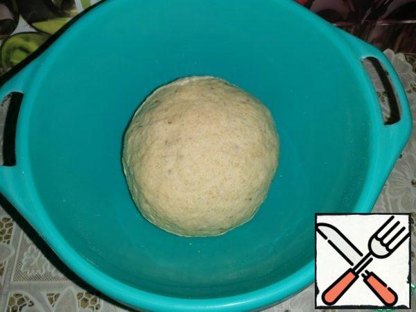 Pour into the dry mixture and knead the dough. Knead until the dough does not fall behind the walls of the bowl. Roll up the bun, cover the bowl with a towel or cling film and leave in a warm place until the dough increases in volume.