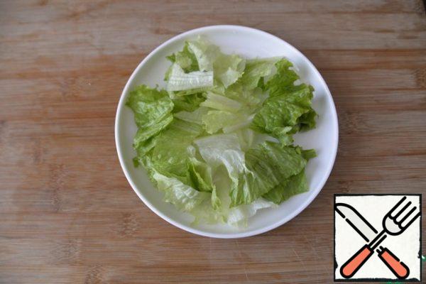 For cooking, we immediately take a plate (dish) in which we will serve the salad. I have half the norm in my photo. Lettuce leaves are washed, dried, torn (or sliced), spread on a plate.