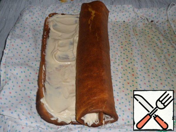 The cooled rolled-up cake is unwound. Spread the prepared curd - caramel cream on the carrot cake. Evenly distribute. Fold the cake in the form of a roll.