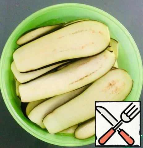 Cut the eggplant lengthwise in strips a little more than 1 cm thick and pour salted warm water (2 tsp salt) for 20 minutes. After such sea baths, they will not be bitter