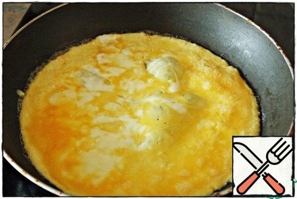 Under the pan, slightly reduce the heat to just below average, put a small piece of butter, evenly distribute over the entire surface and pour the eggs, waiting for the omelet to catch...