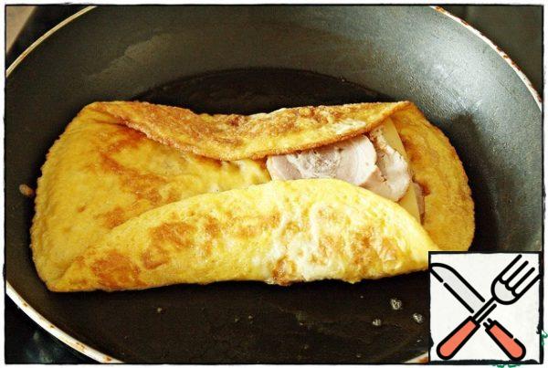 When the croutons are gilded, we need to bend the edges of the omelet along the bread slices with a spatula and cover our filling, pressing the omelet with a spatula so that it does not unfold...