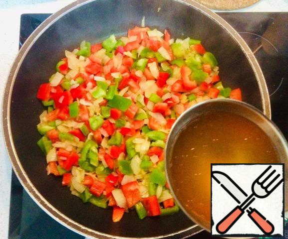 Add half a green pepper and half a red pepper to the onion. Stir, add a little broth and leave to simmer for 10-15 minutes