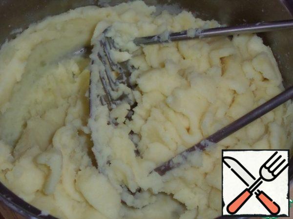 Then we drain the water. In a saucepan, add butter and 100 ml of warm milk. Make mashed potatoes using a potato masher.
