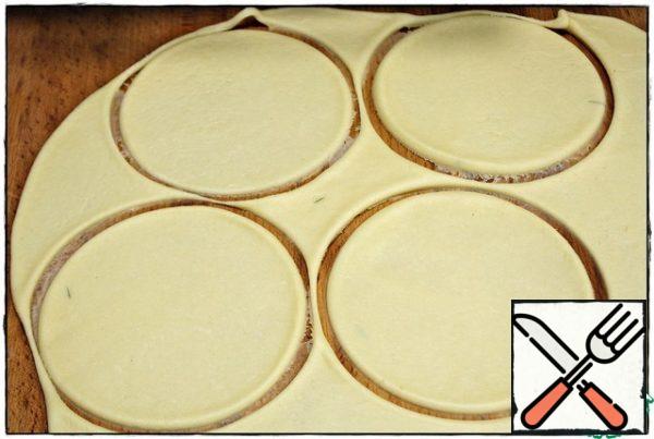 We take some saucer with a diameter of 12-13 mm and squeeze out the blanks. the rest of the dough is removed and we will roll out with the next batch of pies. from the total amount of dough i get 16 such blanks, so count the weight of the filling on about the same number of pies.