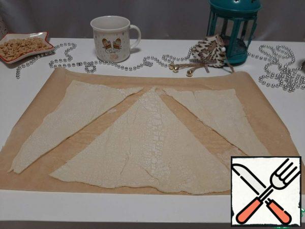 Divide it into two parts. Cut out triangles from one part of the dough layer.