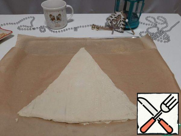 From the second part of the dough, cut out another triangle and spread it on top of the chocolate and peanuts.
