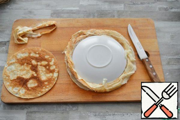 To make the edges of the cake even, cut the pancakes using a plate with a diameter of 18 cm as a template.
