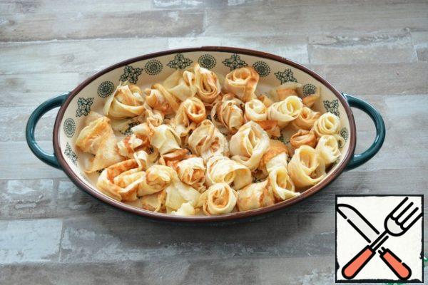 I used pancake trimmings from making pancake cake. But you can also take whole pancakes. If you have scraps, then place them randomly in a baking dish. I screwed up the rolls, but you can just lay them randomly.
If the pancakes are whole, then cut them into ribbons and also put them in a mold