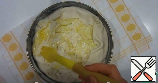 Roll out one layer of dough and put it in a mold with a diameter of 28 cm. Trim the edges.
Spread the filling. the remaining dough on the sides is bent inward.
lubricate the edges with egg.