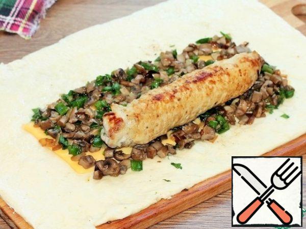 On the onion, put the meat preparation (without toothpicks) and roll the dough layer into a roll.