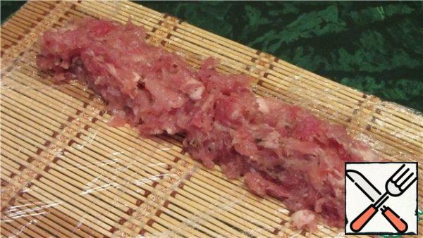 Wrap the mat with food wrap (2-3 layers) and lightly lubricate the surface with vegetable oil. After the specified time, we take out the marinated minced meat from the refrigerator, put an arbitrary amount on the edge of the mat and form future sausages of the desired thickness. The thinner the sausage – the faster it will wither!