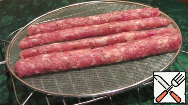 Sausage blanks are laid out on a sieve or a grid from splashes and put on a microwave grill. It is necessary to dry such sausages in the open air, for example, on the windowsill (covering with gauze in 1-2 layers), at a temperature of +18 °C +25°C. The maturation time of dried sausage without a shell depends on the room temperature and the thickness of the formed blanks. This usually takes 4 to 7 days.