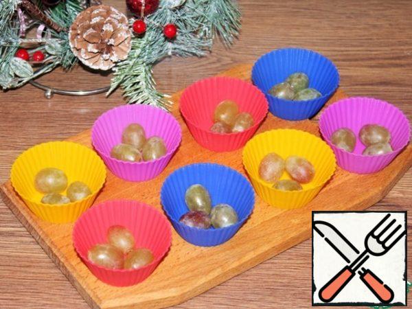 Wash the grapes and dry them with a paper towel. Arrange the grapes in the molds.