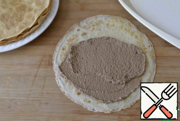 Spread the pancake with pate, retreating from the edge so that it does not come out when folding.