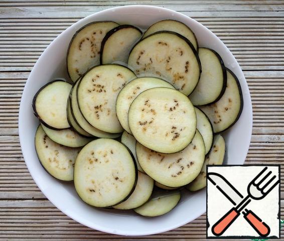 To remove the excess bitterness from the eggplant, pour the circles with salted water and leave for 20 minutes. Then drain the water. Dry the mugs on a paper towel.