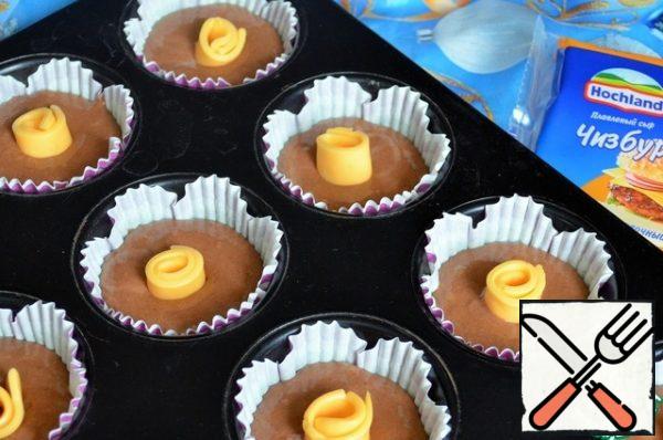Pour the dough into molds, 1/3, roll the cheese and place it in the center of the dough.