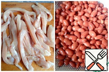 Cut the chicken fillet into strips. Remove the liquid from the beans.