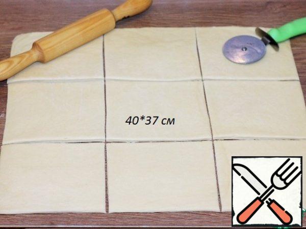 The cooled dough is rolled into a layer, the edges are leveled and cut to a size of ~ 40*37 cm. Scraps roll up and put in a bag. Divide the dough into 9 parts, put it on a cutting Board and cover with a film.
