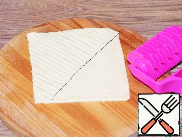 The formed pies. We take 1 part of the dough and cut the mesh into 1/2 part of the rectangle with a curly roller.