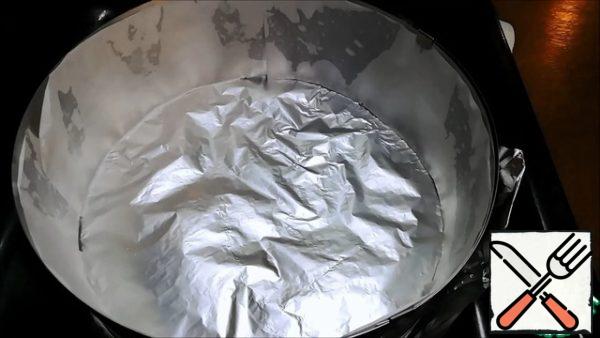 I will bake in a split ring on a baking sheet. I put the foil on the bottom, wrapping the edges up. Inside, the ring was lined with parchment paper, having previously smeared the walls with vegetable oil. The ring diameter is -20 cm. Turn on to preheat the oven to 180 degrees.