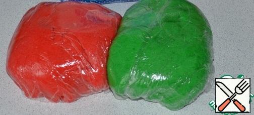 Divide the dough into 2 parts: add green dye to one, red dye to the other.
Wrap the dough in plastic wrap and send it to the refrigerator for 2 hours.