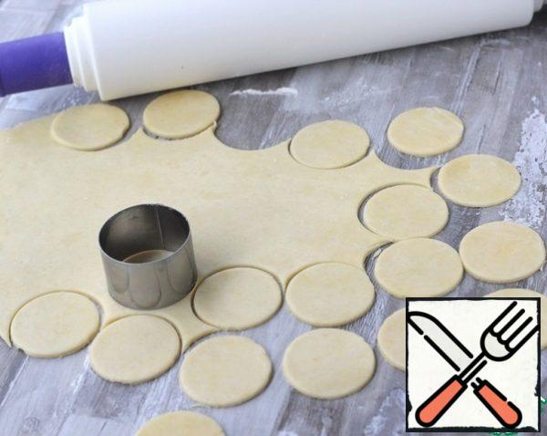 Take the dough out of the refrigerator, cut off half, put the second part back in the refrigerator. Roll out the dough into a layer 3 mm thick, cut out circles with a diameter of 6 cm.