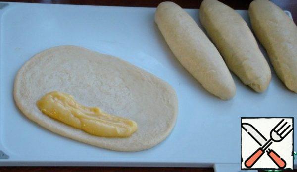 Each piece of dough, roll out in an oval and on one edge along the entire length, distribute the filling from the cooled by this time, orange curd.