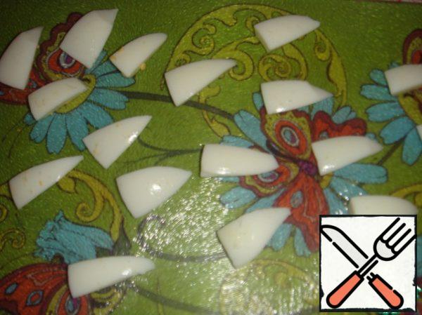 Cut the boiled eggs crosswise into 4 slices, remove the yolk, cut each slice crosswise into 2 parts, and then each triangle - lengthwise. It turns out 16 "petals" from each egg. The inner part of each petal is slightly trimmed – cut off the protruding parts.