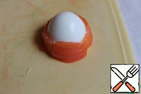 Cut the eggs in half. And then I took only one part of the egg, which we have pointed (you can take quail eggs). Cut the fish into thin strips and wrap it around.