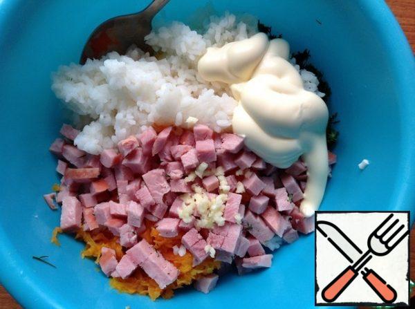 Wash the rice in cold water and allow the excess liquid to drain. Add the rice to the salad, pass the garlic through the press. Cut the ham into small cubes, add sour cream or mayonnaise. Mix gently.