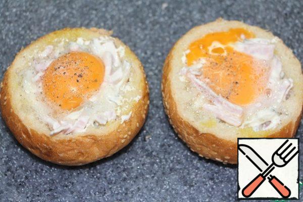 On top of the filling, release the egg, sprinkle the yolk with black pepper.
Bake the buns until the protein thickens. Bake the lids too.