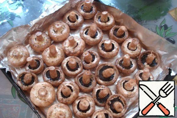 Wash the mushrooms, dry them on a towel, put them in a bowl, pour oil, lemon juice, salt and sprinkle with spices. Let stand for an hour. If the mushrooms are large - two hours. And if they are small, then half an hour will be enough. Place on a baking sheet. I lubricate the foil with oil.