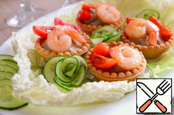 In tartlets, put the cream of avocado and garlic, add shrimp, cherry tomatoes slices. Place fresh lettuce leaves on a platter. Add to the snack decorations in the form of roses from fresh cucumber.