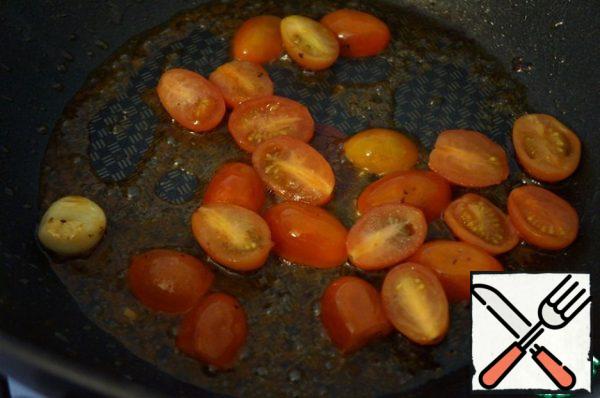 Place the shrimp on a paper napkin. In the same pan, send a clove of garlic, cherry tomatoes, cut in half and the remains of the marinade from the shrimp. Fry for half a minute.