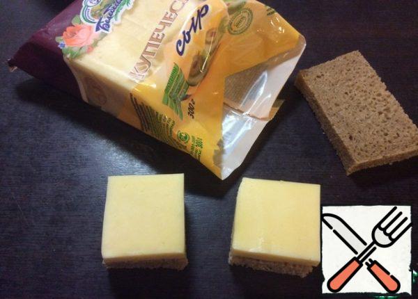 Cut the crust off a slice of bread. Put a piece of cheese on a piece of bread, adjust the size of the slice and cut each slice of bread into 4 parts.