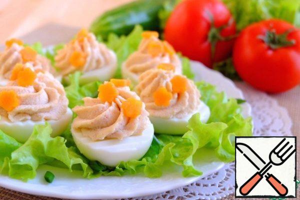 Fill the egg halves with the prepared cream. Boil the carrots, cut out the flowers with a curly cutting. Decorate the appetizer with carrot flowers. Place the appetizer on a platter with lettuce leaves. Sprinkle with green onions.