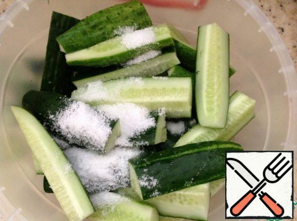 In cucumbers, cut off the buttocks and cut the cucumbers themselves into cubes. Put it in our bowl. Pour salt and sugar on top of the cucumbers. Close the lid tightly.