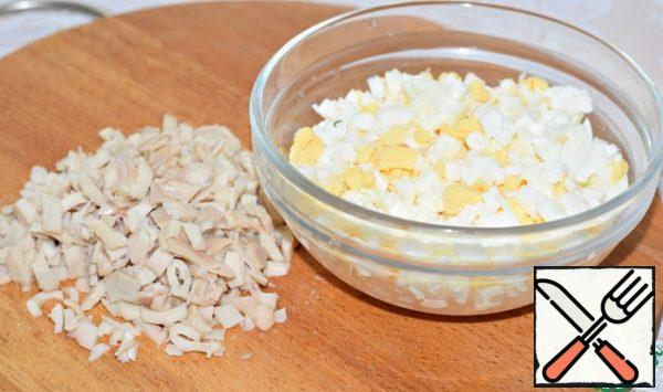 Chop the eggs.
Drain the liquid from the canned squid and finely chop it.
Instead of canned, you can use boiled squid. A very decent alternative.
