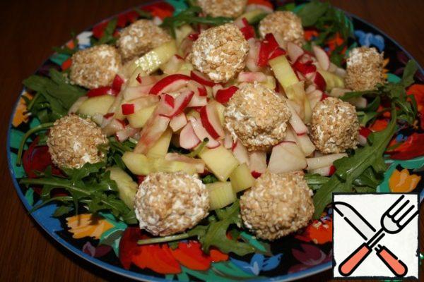 Cut the cucumber and radish into strips, mix with the dressing.
Place the arugula on a platter, then add the radish and cucumber and garnish with balls.