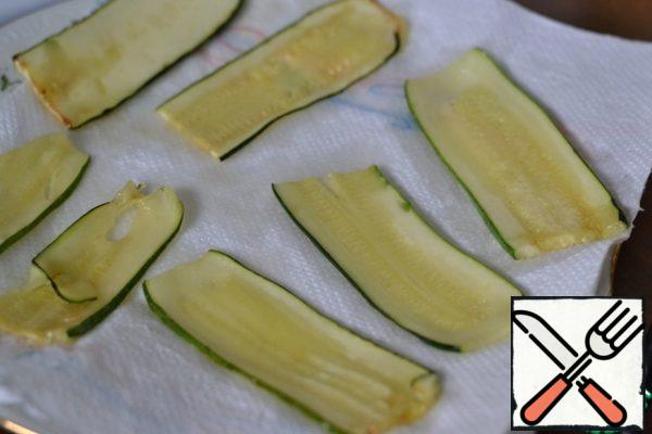 Fried zucchini spread on a kitchen napkin. Leave to cool completely.