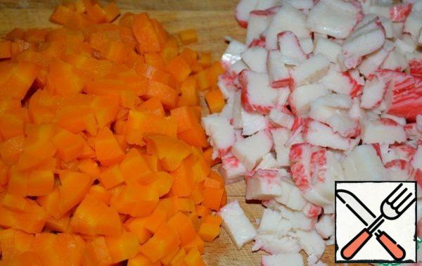 Cut the carrots and crab sticks into cubes.