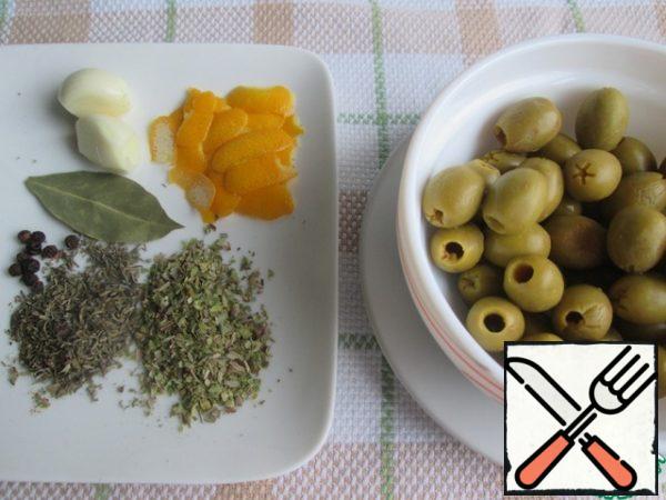Remove the olives from the jar, drain the liquid.
Remove the zest from the lemon with a vegetable peeler, in wide strips.
Prepare dried herbs, bay leaf, black pepper and garlic.