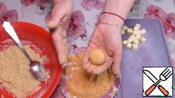 We form balls with wet hands.
In the palm of your hand, spread 1/2 tbsp. l. potato dough, shape it into a tortilla, put 1 piece of cheese on top and roll it into a ball.
Roll the balls in breadcrumbs.
